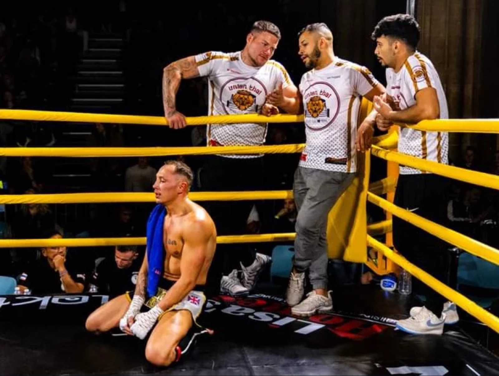 Union Thai cornermen leaning over the ropes coaching a fighter